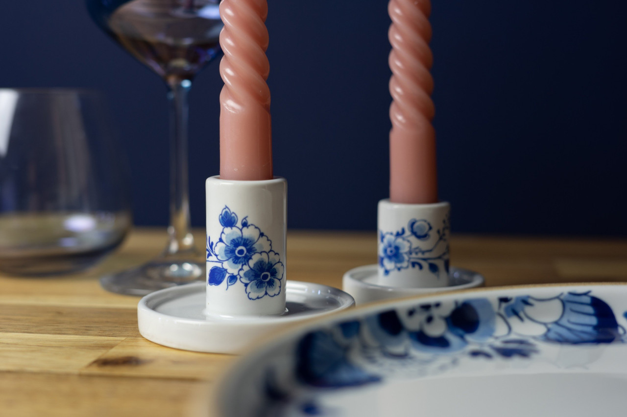 Een gedekte tafel met twee Delfts blauwe kandelaars met bloem decoratie