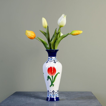 Slank vaasje met een witte achtergrond met onderaan en bovenaan Delfts blauw versiering. In het midden van de vaas rondom oranje tulpen.
